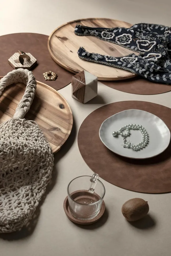 Stilisierter Tisch mit Kerzen, Vase und Buch in warmen Farbt&ouml;nen