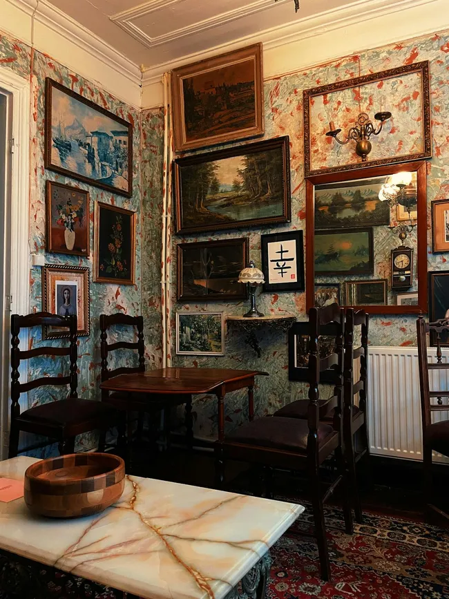 Stimmungsvolles Wohnzimmer mit Vintage-Holzmöbeln, klassischen Kunstwerken und warmen Textilaccessoires im gelungenen Stilmix